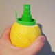 Hand holding a lemon into which a Stem Citrus Sprayer attachment has been screwed